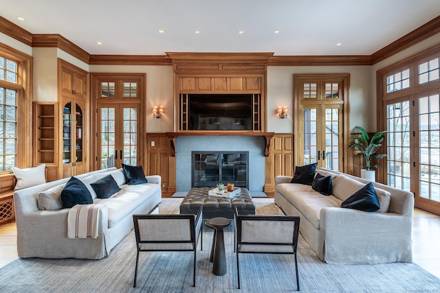 living room featuring french doors, wainscoting, crown molding, and wood finished floors