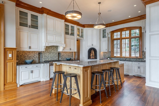 kitchen featuring wood-type flooring, stainless steel range, backsplash, and a center island