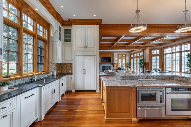 kitchen with a warming drawer, appliances with stainless steel finishes, a sink, wood finished floors, and coffered ceiling