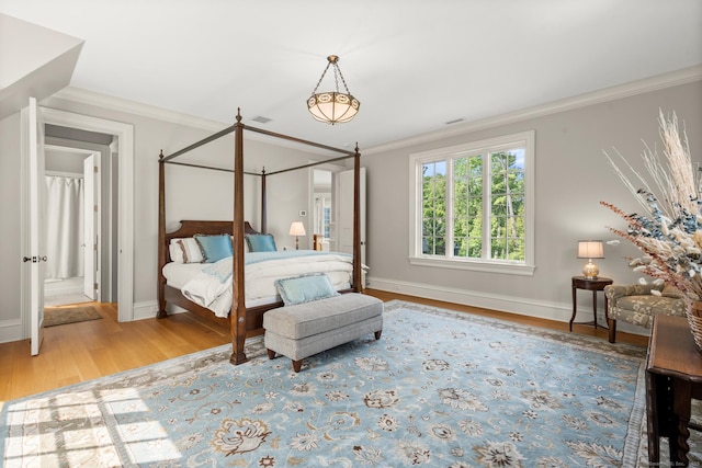 bedroom with baseboards, visible vents, ornamental molding, and wood finished floors