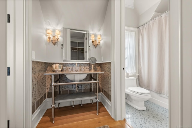 bathroom with curtained shower, toilet, wainscoting, a sink, and wood finished floors