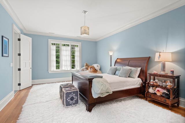 bedroom featuring crown molding, baseboards, and wood finished floors