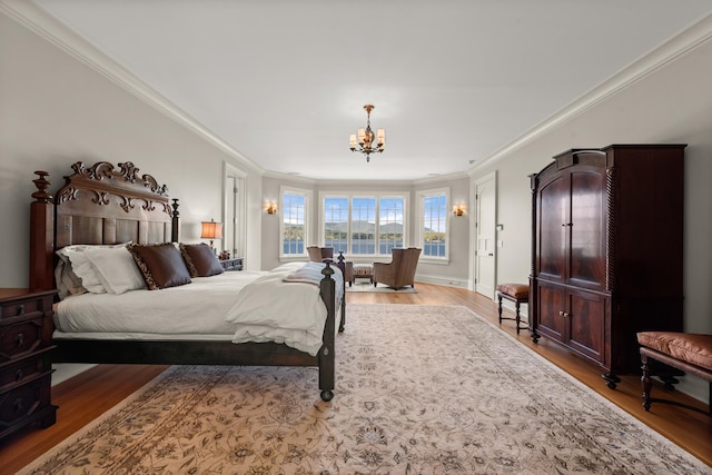 bedroom featuring baseboards, ornamental molding, wood finished floors, and an inviting chandelier