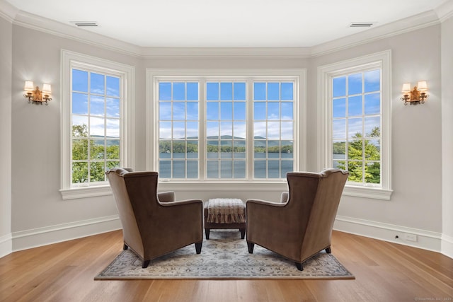 living area with visible vents, baseboards, wood finished floors, and ornamental molding