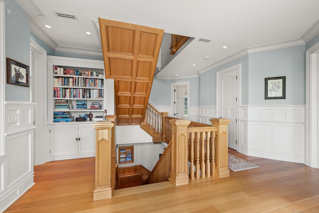 interior space featuring light wood-style flooring, built in shelves, visible vents, and wainscoting