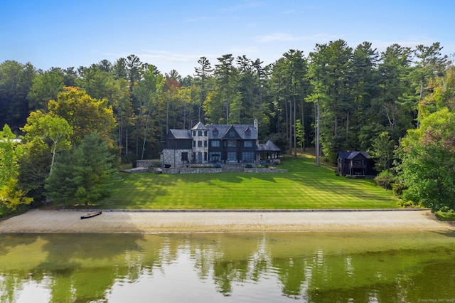 rear view of property with a water view, a view of trees, and a lawn