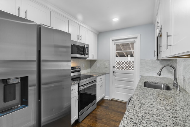 kitchen featuring light stone countertops, white cabinetry, stainless steel appliances, and a sink