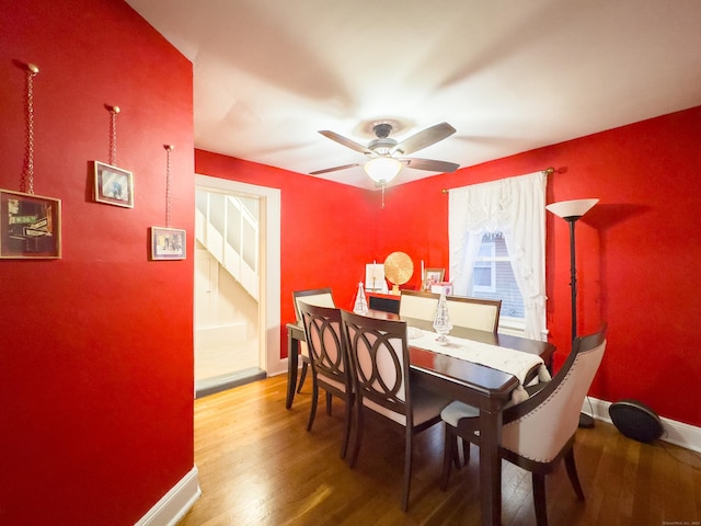 dining space with a ceiling fan, baseboards, and wood finished floors