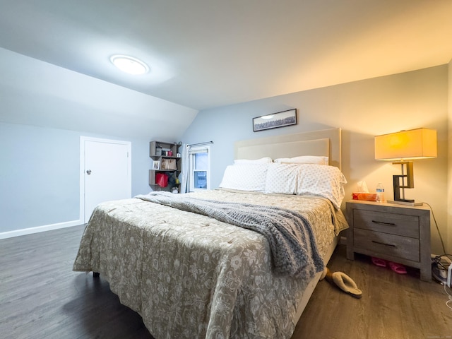 bedroom with baseboards, vaulted ceiling, and wood finished floors