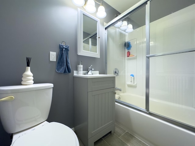 full bathroom featuring combined bath / shower with glass door, vanity, and toilet