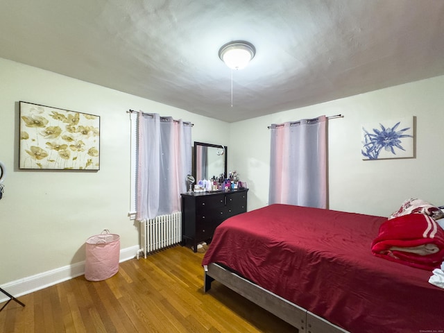 bedroom featuring baseboards, wood-type flooring, and radiator