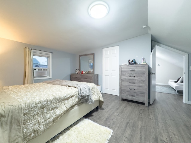 bedroom featuring lofted ceiling, a closet, cooling unit, and wood finished floors