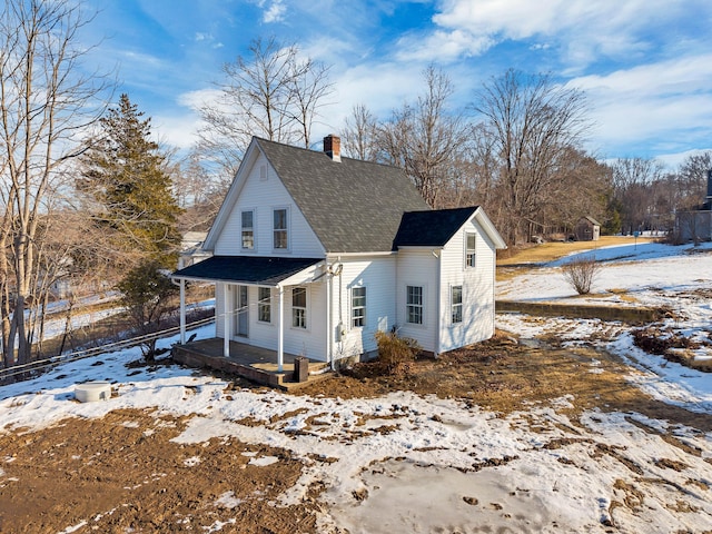 view of front of house with a chimney, a porch, and roof with shingles