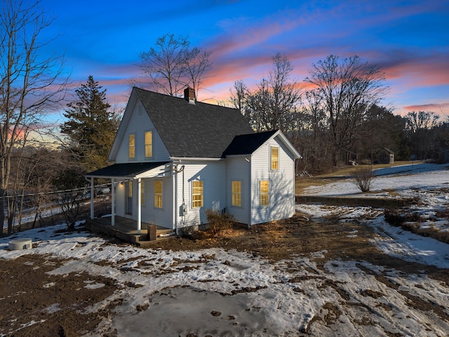 exterior space featuring covered porch, a shingled roof, and a chimney