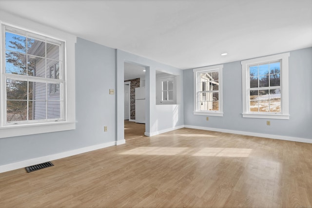 unfurnished living room with light wood-style flooring, visible vents, and baseboards