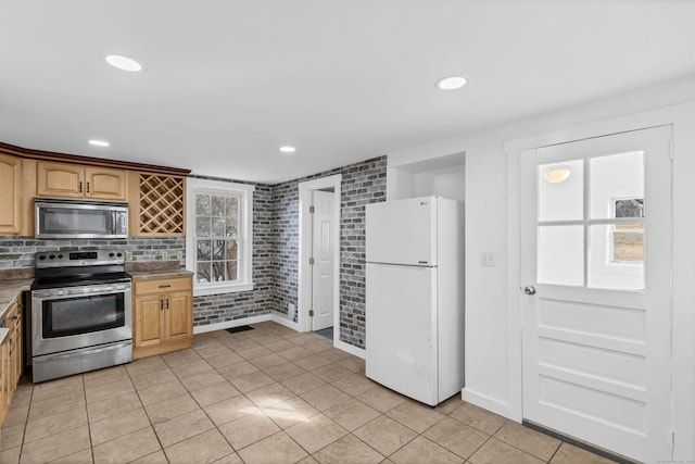 kitchen with light tile patterned floors, recessed lighting, stainless steel appliances, brick wall, and backsplash