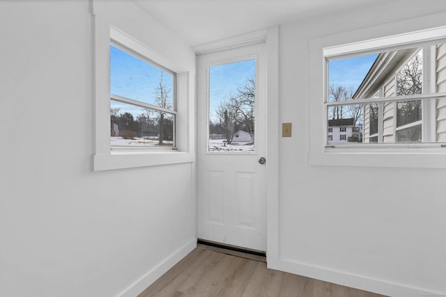 entryway featuring baseboards, light wood finished floors, and a healthy amount of sunlight