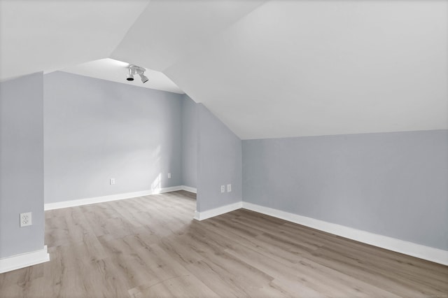 bonus room featuring lofted ceiling, light wood-style flooring, and baseboards