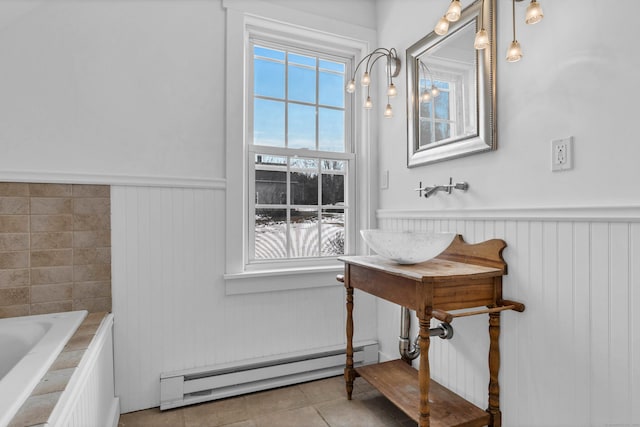 bathroom featuring wainscoting, a baseboard radiator, tile patterned flooring, and a tub