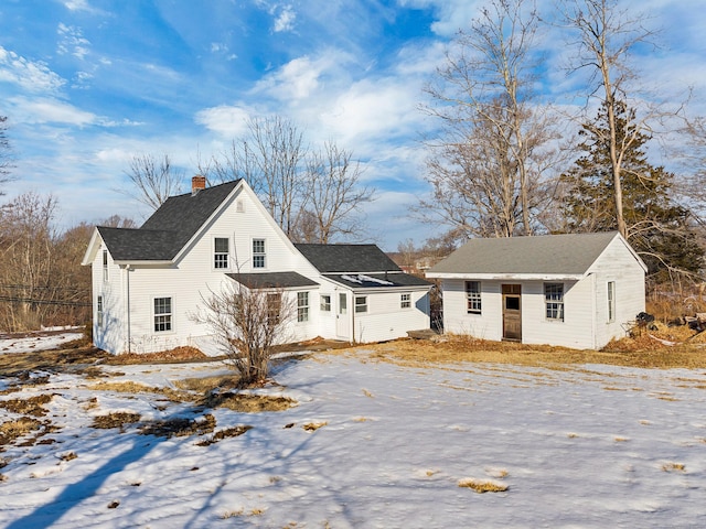 exterior space with a shingled roof, a chimney, and an outdoor structure