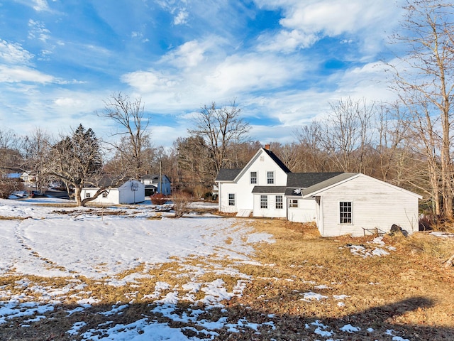 snow covered rear of property with an outbuilding and a shed