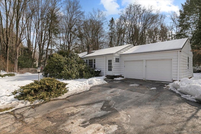 view of front of house featuring a garage, a chimney, and aphalt driveway