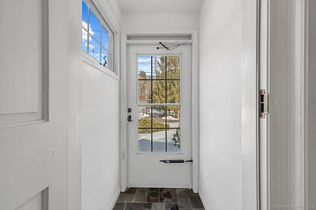 doorway to outside with stone finish flooring and baseboards