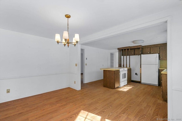 kitchen featuring hanging light fixtures, white appliances, light wood finished floors, and light countertops