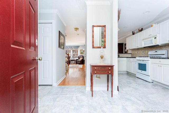 kitchen with crown molding, dark countertops, decorative backsplash, white cabinets, and white appliances