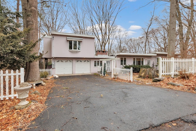 view of front of home featuring a fenced front yard, an attached garage, and aphalt driveway