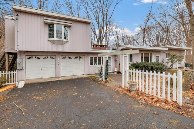 view of front of house featuring aphalt driveway, an attached garage, and fence