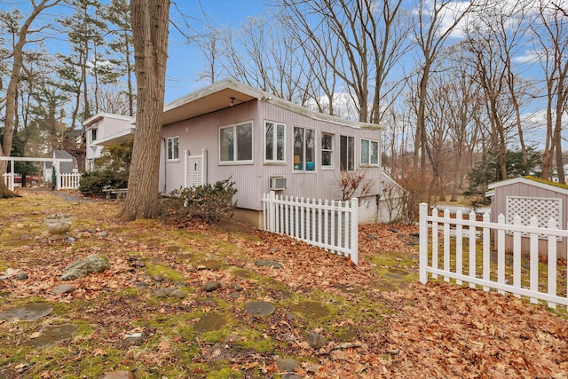 view of property exterior featuring a storage unit, fence, and an outdoor structure