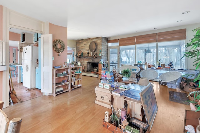 living area with light wood-style floors, a baseboard heating unit, and a fireplace