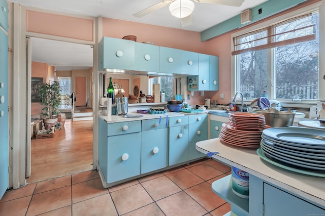 kitchen with a healthy amount of sunlight, light tile patterned floors, light countertops, and a sink