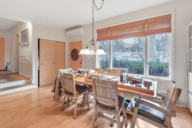 dining space featuring plenty of natural light, light wood-style flooring, an inviting chandelier, and a wall mounted AC