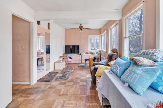 living area with ceiling fan, beam ceiling, and baseboards