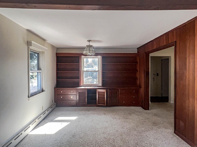 spare room with light carpet, baseboard heating, and wooden walls