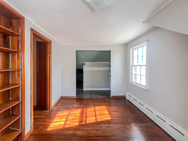 unfurnished room featuring built in shelves, a baseboard radiator, wood finished floors, and baseboards