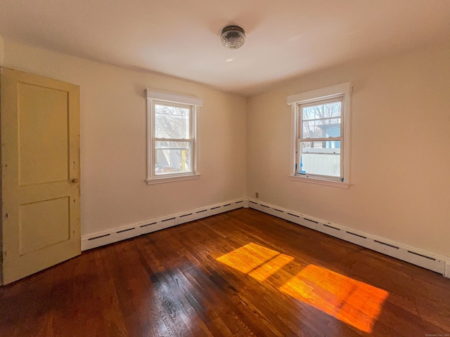 spare room featuring baseboard heating, wood-type flooring, and a wealth of natural light