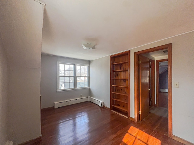 unfurnished room featuring built in features, a baseboard heating unit, and wood finished floors