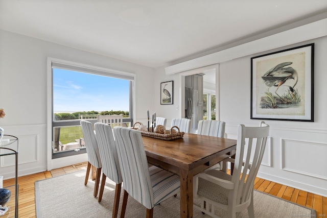 dining space featuring light wood-style floors, a healthy amount of sunlight, and a decorative wall