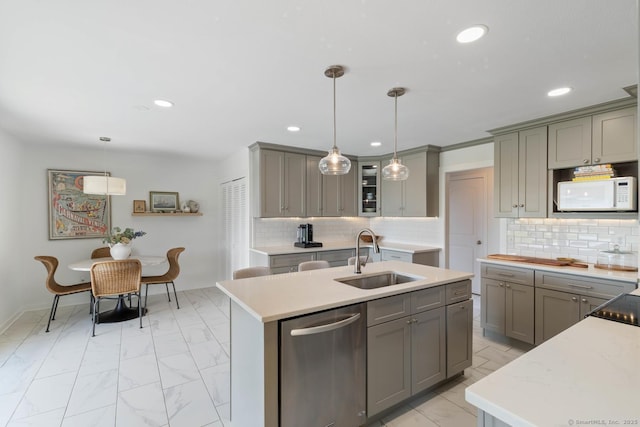 kitchen with hanging light fixtures, stainless steel dishwasher, white microwave, glass insert cabinets, and a sink