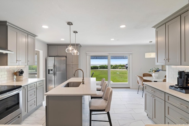 kitchen featuring gray cabinets, light countertops, hanging light fixtures, appliances with stainless steel finishes, and a sink