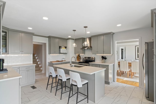 kitchen featuring marble finish floor, light countertops, gray cabinetry, appliances with stainless steel finishes, and a sink