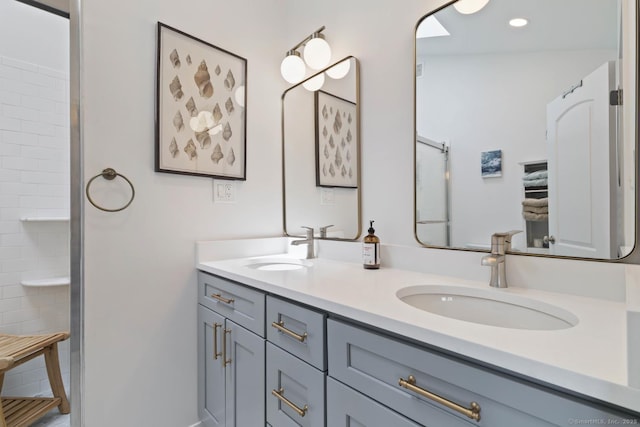 bathroom featuring a shower, recessed lighting, a sink, and double vanity