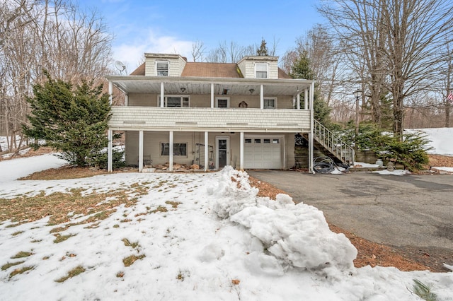 view of front of home with driveway, a garage, stairway, and a porch