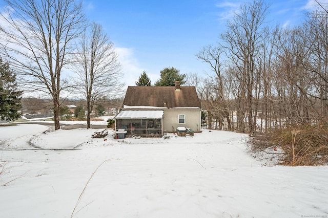 snow covered house featuring a sunroom