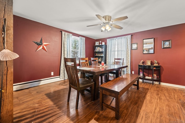 dining area featuring a baseboard heating unit, wood finished floors, a ceiling fan, and baseboards