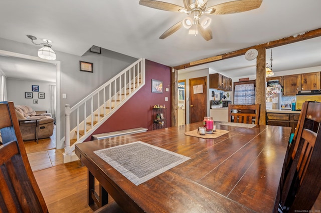 dining room with ceiling fan, stairway, and wood finished floors