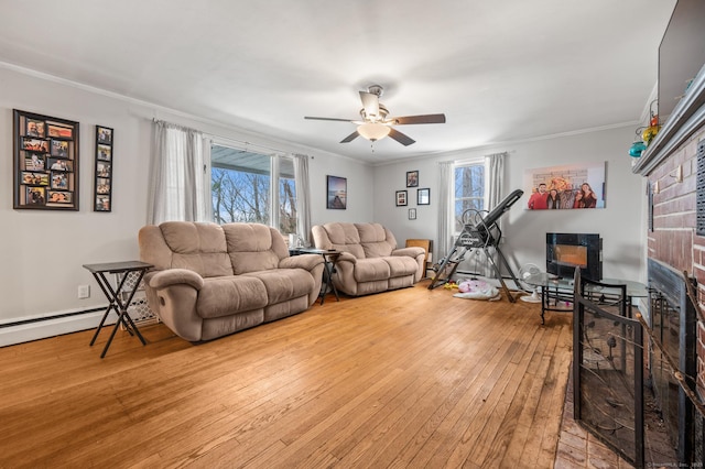 living room with ornamental molding, a fireplace, light wood-style flooring, and a ceiling fan